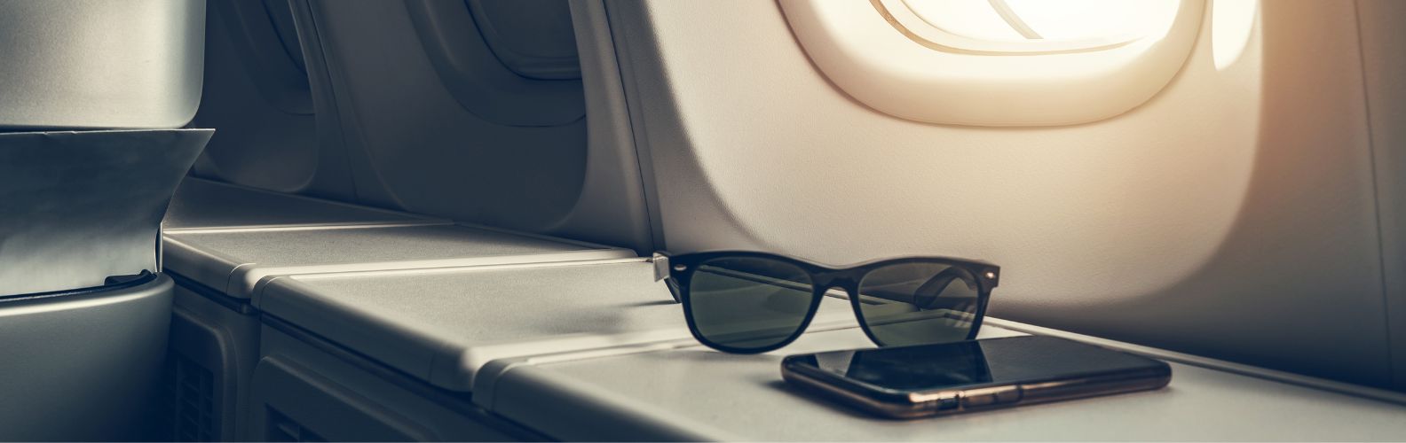 Siège en classe affaires avec smartphone et lunettes, symbolisant le confort offert par le visa privilège Thaïlande.