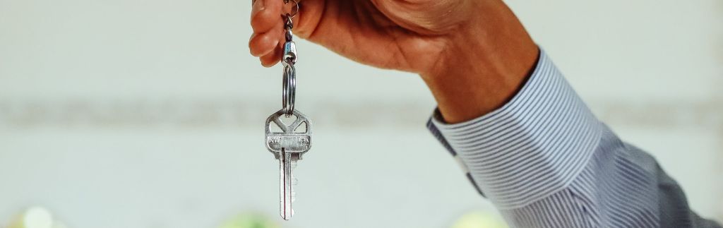 Main tenant une clé, illustrant la nécessité d’une assurance biens en Thaïlande lors d’une acquisition immobilière