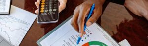 Two people analyzing financial charts and using a calculator during a meeting about Thailand investment funds.