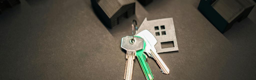 Keys with a house-shaped keychain on a dark surface, symbolizing secure property registration through the Thailand Land Registry.