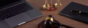 Scrivania con bilancia della giustizia, martelletto e computer portatile, simbolo della legge sull’età del consenso in Thailandia.