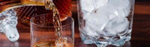 Bicchiere di whisky versato con cubetti di ghiaccio, simbolo delle leggi sugli alcolici in Thailandia.