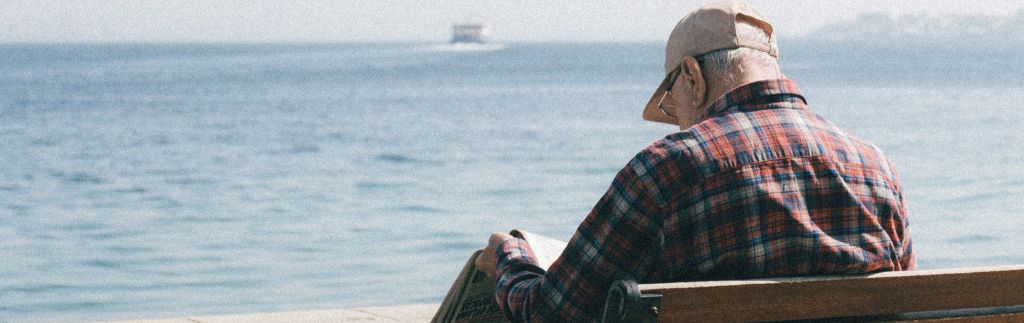 Uomo anziano seduto su una panchina fronte mare, simbolo della tranquillità e dello stile di vita offerto dal visto pensionati Thailandia.