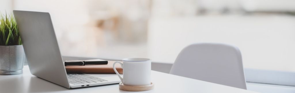 Moderner Schreibtisch mit Laptop, Kaffeetasse und Pflanze – Symbol für einen professionellen Arbeitsplatz in Thailand im Zusammenhang mit Arbeitsvertrag Thailand.