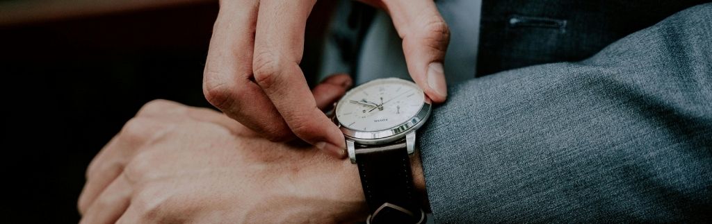 Geschäftsmann überprüft seine Uhr – Symbol für Arbeitszeiten Thailand und Einhaltung der Arbeitszeitregelungen.