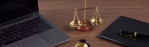 Bilancia della giustizia, computer portatile e penna su una scrivania, simbolo del diritto del lavoro e delle normative sui lavoratori stranieri in Thailandia.