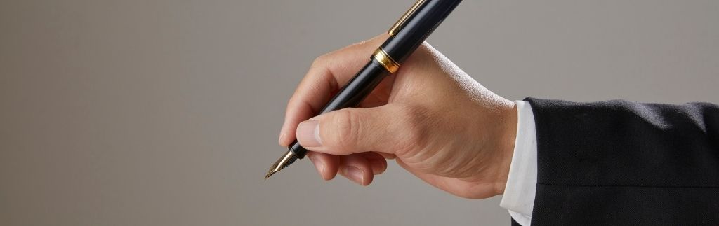 Mano che firma un documento legale, simbolo della certificazione e legalizzazione della traduzione inglese in Thailandia