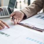 Business meeting analyzing financial reports and tax documents related to capital gain tax in Thailand