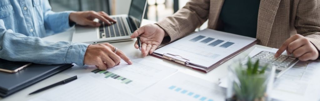 Business meeting analyzing financial reports and tax documents related to capital gain tax in Thailand