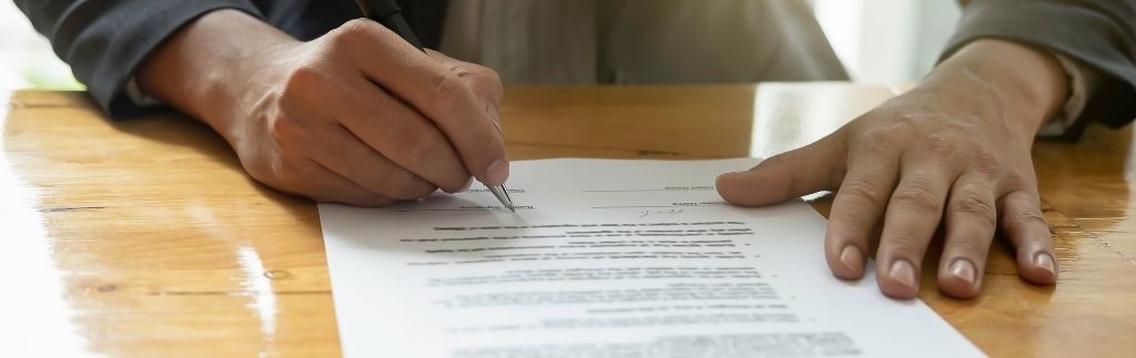 Person signing a TM7 Form document to extend a visa in Thailand.