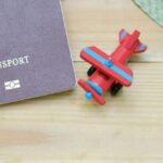 Семейная виза Таиланд для супругов и детей LTR, паспорт и игрушечный самолет на деревянной поверхности.