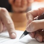 Two people signing a legal document related to foreigners working in Thailand.