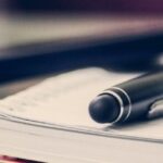 Pen and TM30 Thailand form on a desk, symbolizing immigration reporting procedures.