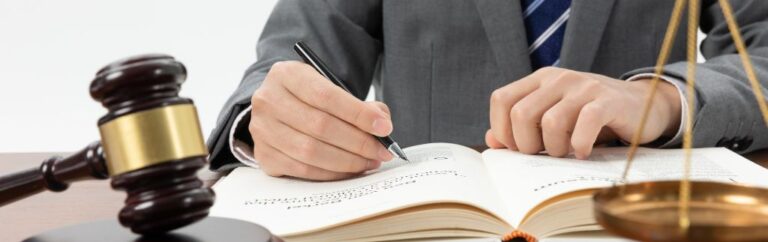 Lawyer reviewing legal documents with gavel and scales of justice on desk, illustrating consumer protection Thailand and regulatory compliance.