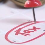 Kalender mit markiertem Steuertermin und Stecknadel als Symbol für die Quellensteuer in Thailand