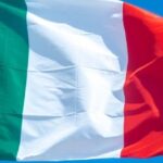 Bandiera italiana che sventola nel cielo azzurro, immagine utilizzata in un articolo sui pensionati italiani in Thailandia.