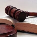 Деревянный судейский молоток, лежащий на раскрытой юридической книге, символизирующий правовое регулирование пенсионного статуса в Таиланде.