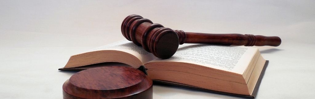 Деревянный судейский молоток, лежащий на раскрытой юридической книге, символизирующий правовое регулирование пенсионного статуса в Таиланде.